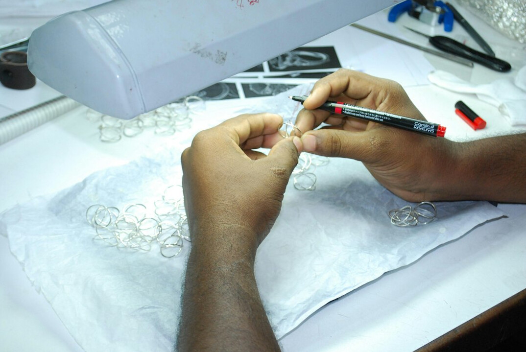 Close-up of hands reviewing printed documents with a pen and magnifying glass